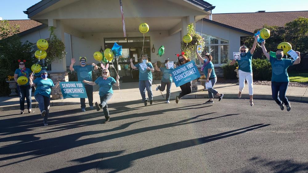 Photo of team wearing matching shirts jumping joyfully with fun balloons and signs.