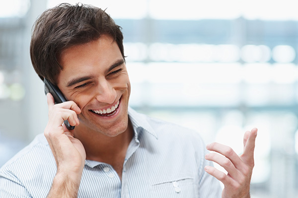 A man smiling while he talks on the phone