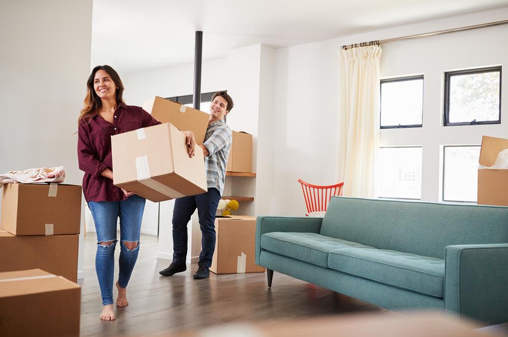Young adult woman and man moving boxes into a new home.