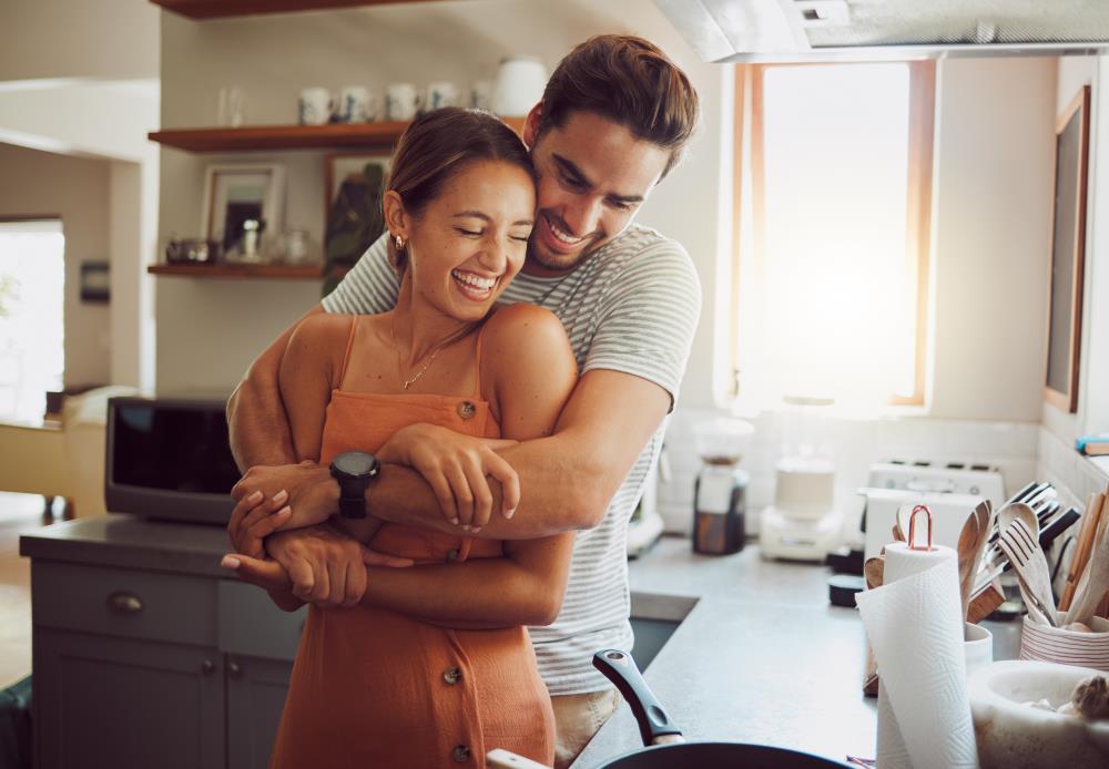 Man and woman hugging in kitchen.