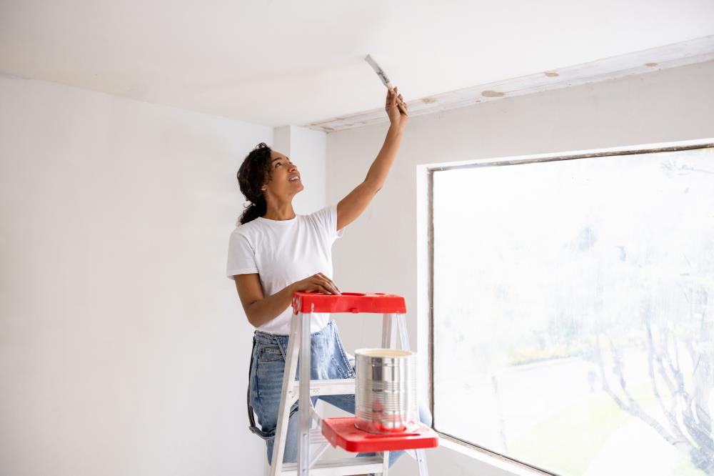 Female Making Home Improvements - Painting Ceiling