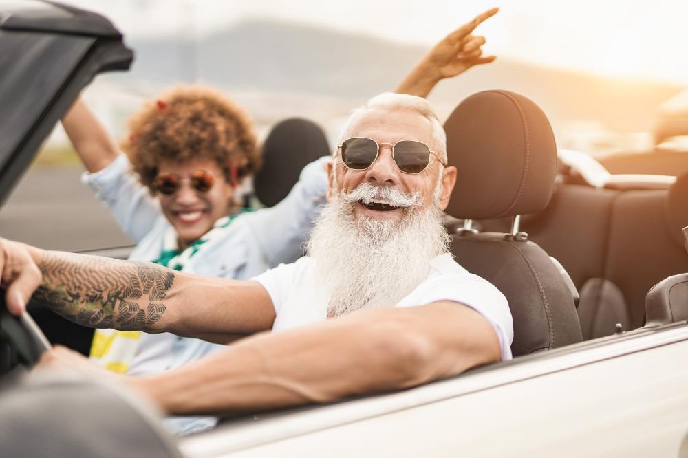 Excited hispanic couple driving in convertible on the highway 