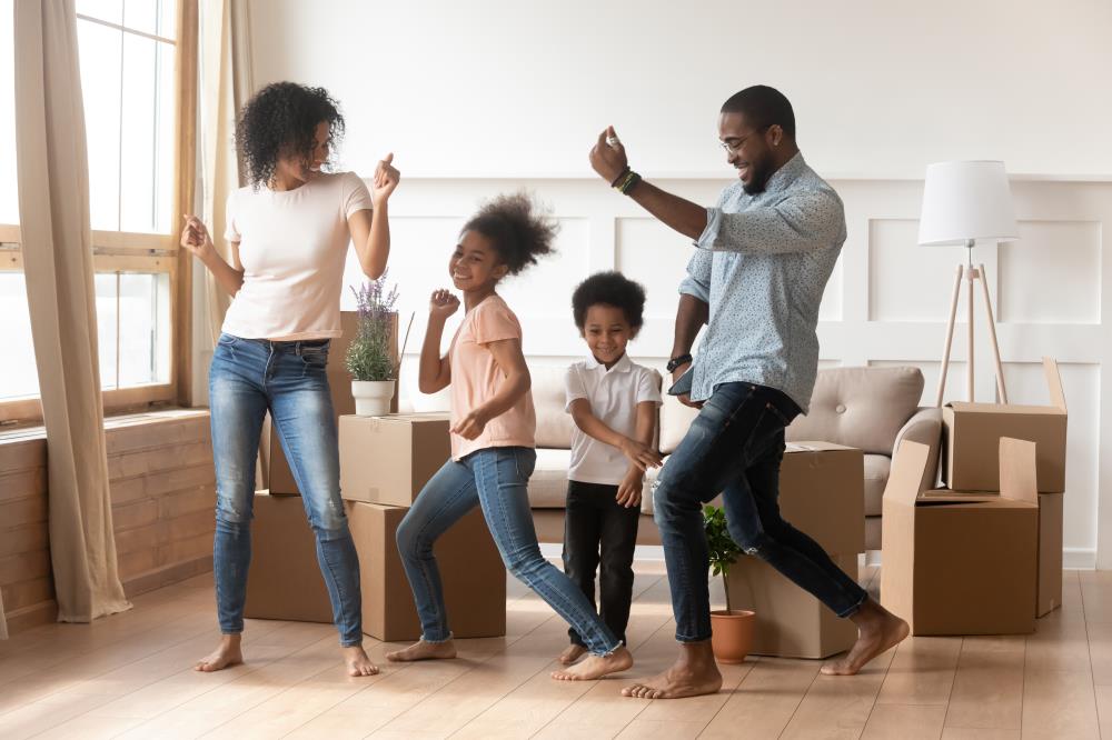 Family dancing barefoot celebrating move-in to new home