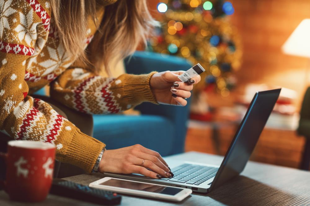 Woman at laptop with card and holiday background