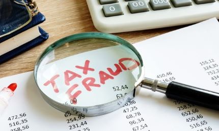 Magnifying glass on the words Tax Fraud - links to fraud prevention article